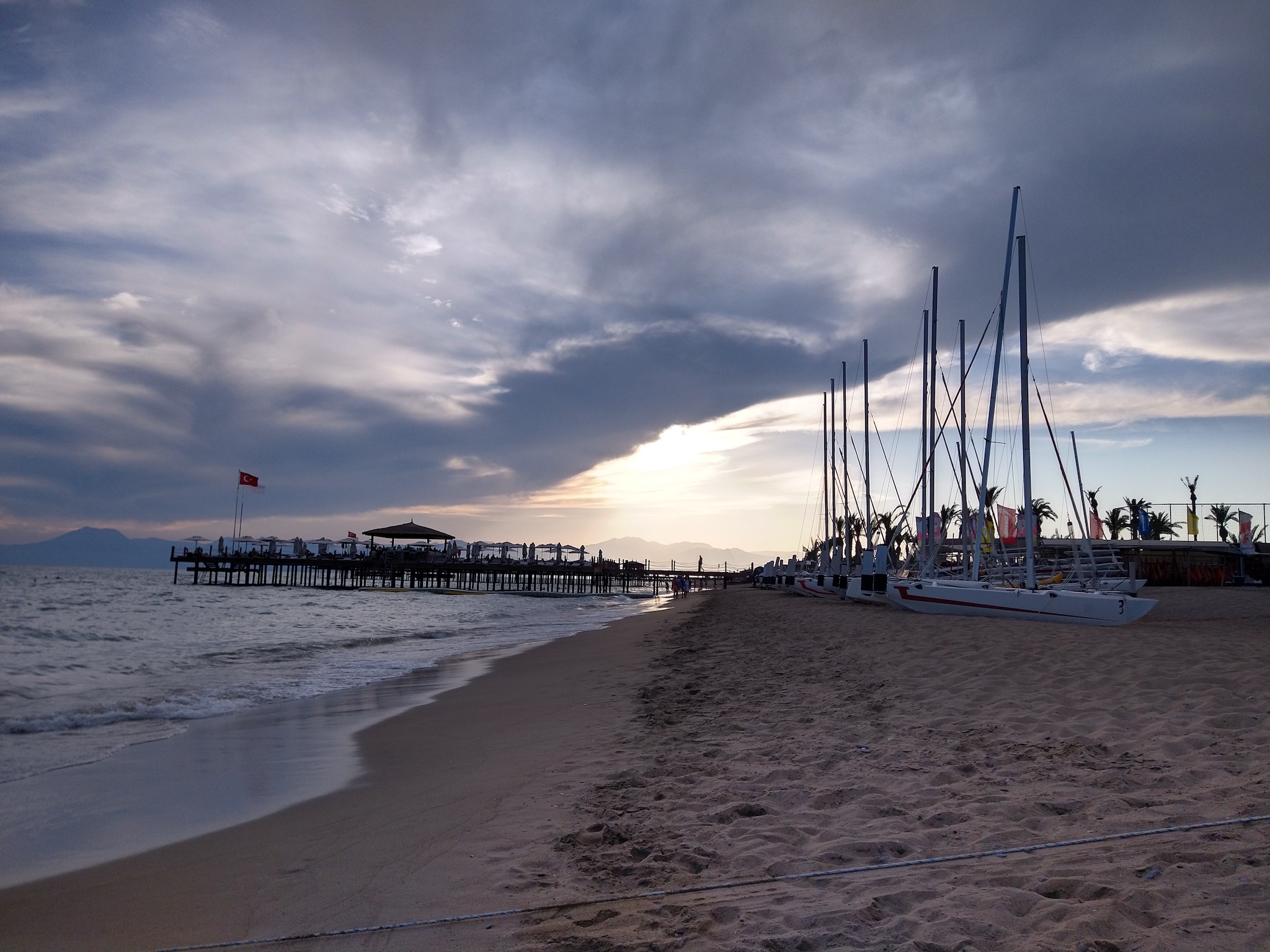 Boats sitting on a beach at sunset