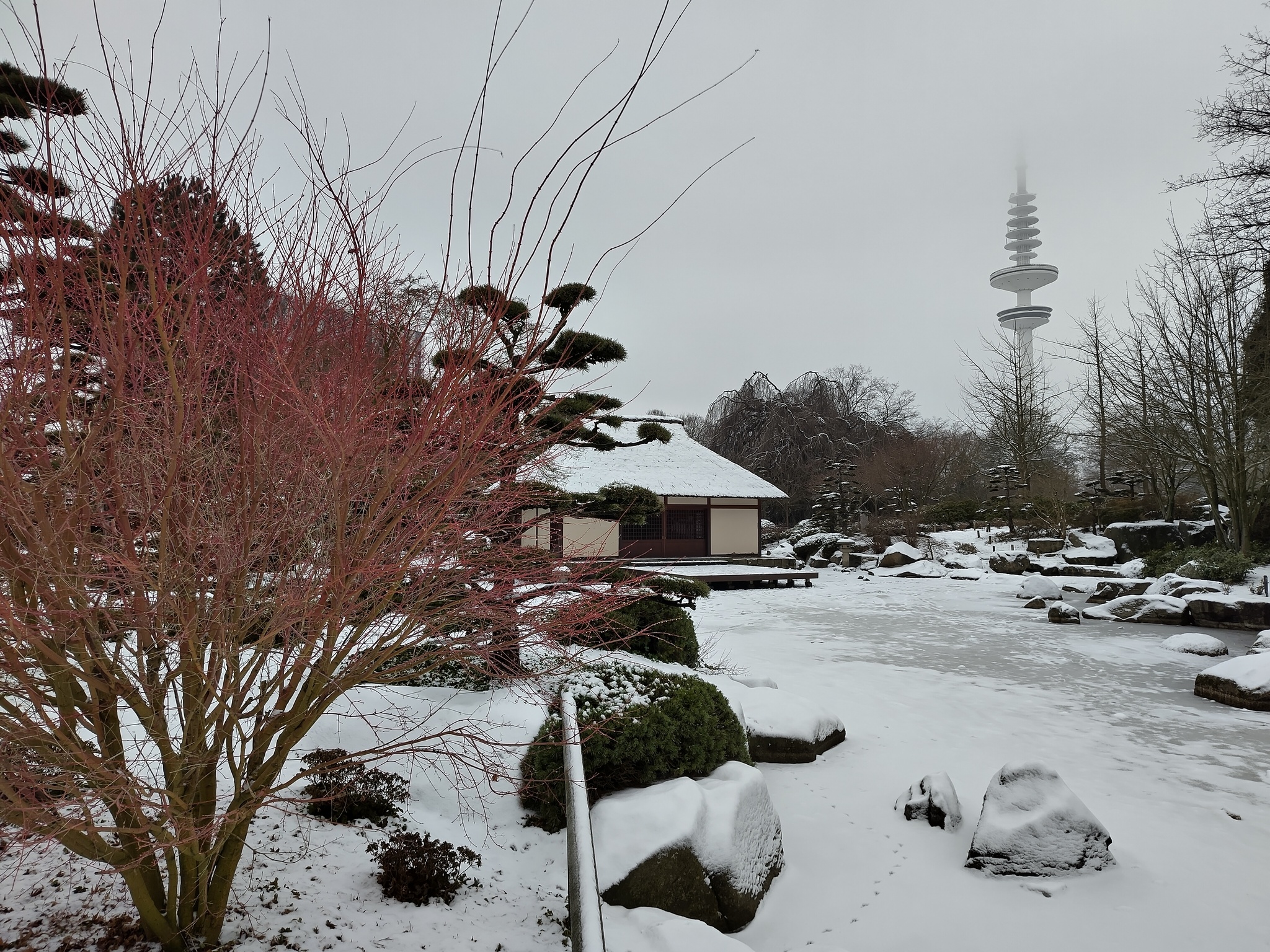 Photo of a Japanese Garden, showing a small house, all covered with snow.